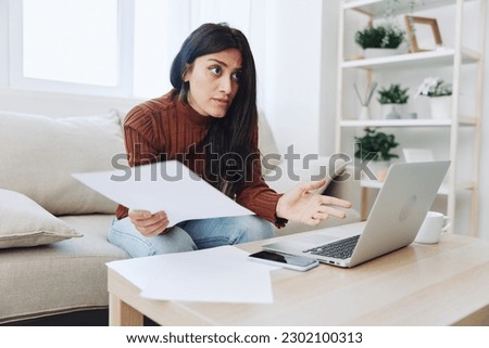A sad freelance woman with a laptop on her desk works online from home shrugs her hands in incomprehension