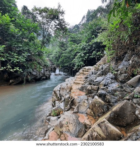 The flow of the Cibaliung Curug river is clear with access to slippery rocks.