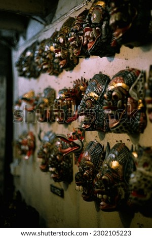  Colorful Asian monkey, demon, and dragon masks hanging on the wall, one mask in focus
