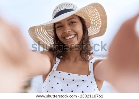 Young african american woman wearing summer hat make selfie by camera at seaside