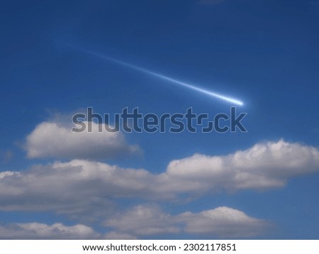 Meteorite in the daytime against the blue sky. Bright meteor in daylight. A beautiful shooting star between the clouds.