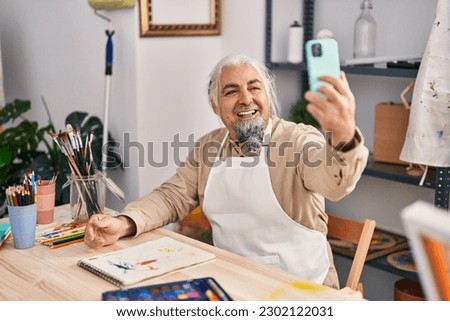 Middle age grey-haired man artist smiling confident make selfie by smartphone at art studio