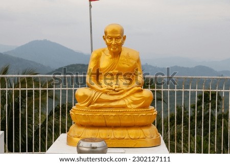 golden sculpture of an elderly buddhist near the big buddha statue on phuket island in thailand