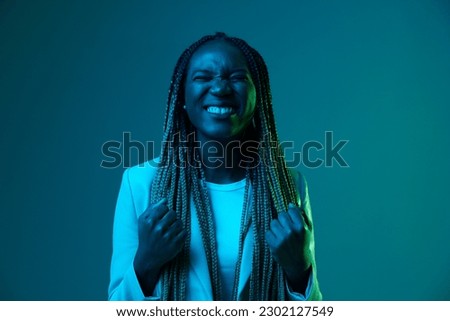 African american woman portrait business smile and fashion wearing glasses on blue background in neon light, color mixed light, bright color dancing, futuristic party. Flying pigtails hair emotions.
