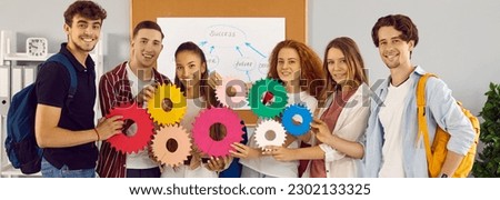Team of male and female students work on project together. Group portrait of happy young people looking at camera, joining colorful gears and smiling. Education, integration, teamwork, success concept