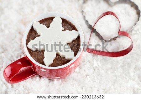 Above shot of a vibrant red cup of hot chocolate with snow flake shape of whipped cream or marshmallow. Extreme shallow depth of field.