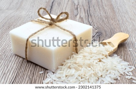 A bar of natural soap and rice stack on a wooden table, closeup