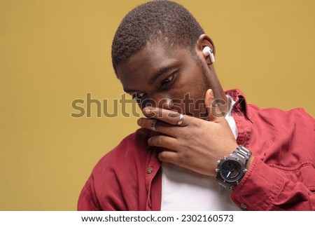 young African American man pictured isolated on gray background wearing casual clothes and hat dancing to music he is listening through wireless earphones, feeling relaxed and happy