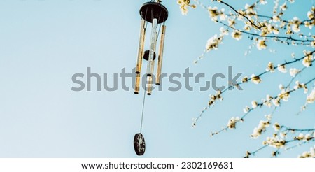 Wind chime with zen symbolism hanging on tree in blossom with copy space Royalty-Free Stock Photo #2302169631