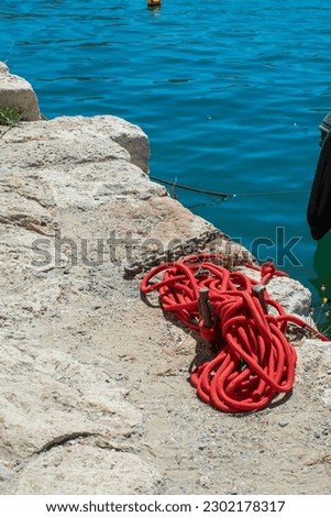 Red rope lies on a stone pier. Mediterranean sea