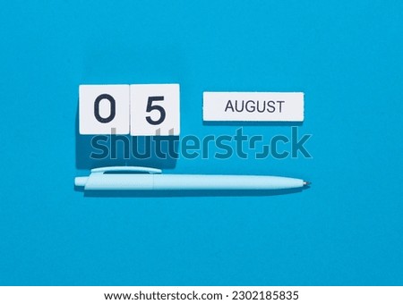 White cube calendar with date august 05 with pen on blue background. Deadline, business concept Royalty-Free Stock Photo #2302185835