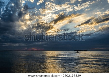 Sky in various colors of yellow, red, blue and white with water illuminated.