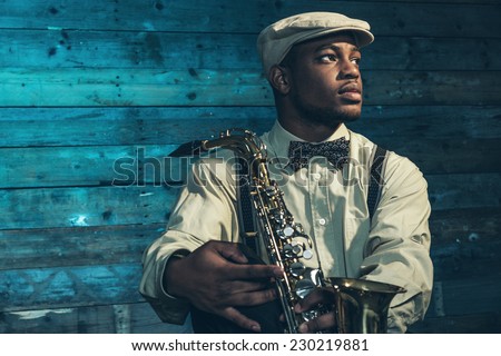 African american jazz musician with saxophone in front of old wooden wall. Royalty-Free Stock Photo #230219881