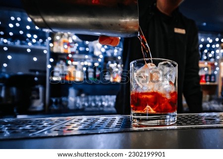 man bartender hand making negroni cocktail. Negroni classic cocktail and gin short drink with sweet vermouth, red bitter liqueur Royalty-Free Stock Photo #2302199901