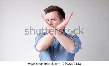 European young man shows a stop sign with his hands Royalty-Free Stock Photo #2302217133
