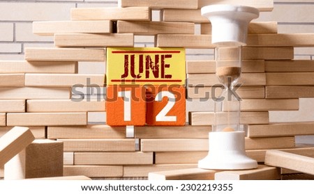 June 12 calendar date text on wooden blocks with blurred nature background. Copy space and calendar concept.