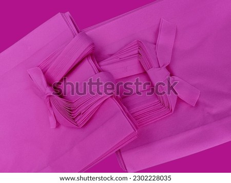pile of two packs of porous pink tote bags. non-woven fabric tied with rope. polypropiline bag on purple background