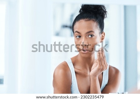 Skin care, black woman with cotton wipe on face and makeup cleaning with luxury cosmetic product in bathroom. Dermatology, cosmetics and beauty facial, African model with cleansing pad and mock up. Royalty-Free Stock Photo #2302235479
