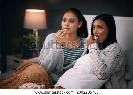 Popcorn, eating and women or friends with horror movies, scary show and sleepover on bed, streaming service or television. Gen z people relax in bedroom for drama TV film, home cinema or subscription