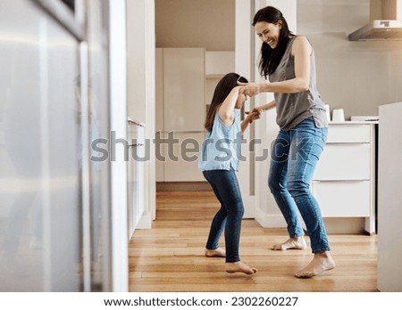 Holding hands, dance and a child with a mother in the kitchen, bonding and quality time together. Smile, laughing and a mom teaching her daughter with dancing, love and happiness with fun in a house Royalty-Free Stock Photo #2302260227