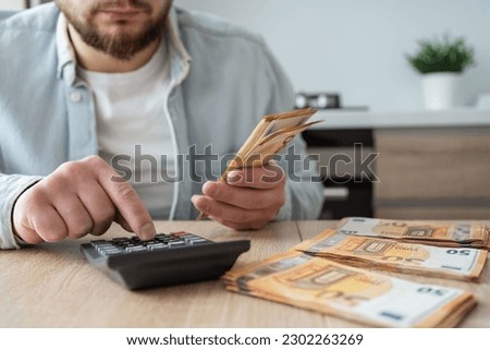 Serious man counting money at home.
 Royalty-Free Stock Photo #2302263269