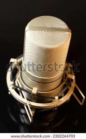 Champaign colored condenser microphone on a glossy black surface