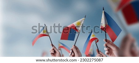 A group of people holding small flags of the Philippines in their hands. Royalty-Free Stock Photo #2302275087