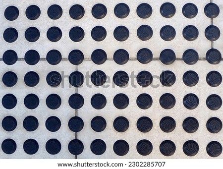 Black plastic anti slip studs in a tile walkway