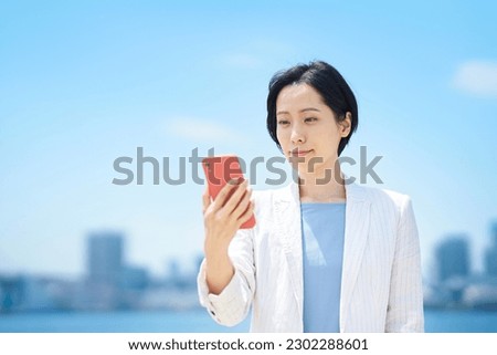Business woman with smartphone outdoors in sunny weather