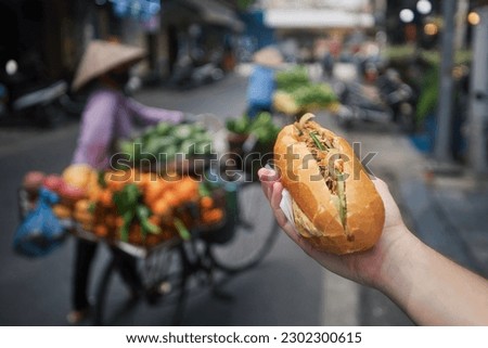 Street food in Hanoi. Hand holding Banh Mi sandwich. Close-up of traditional Vietnamese baguette filled with pate, meat and vegetables.
 Royalty-Free Stock Photo #2302300615
