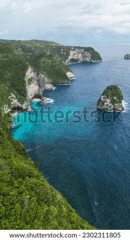 Vertical picture from the drone. Picturesque view to the Nusa Penida cliffs. Amazing turquoise ocean water. Green jungle. Nature background