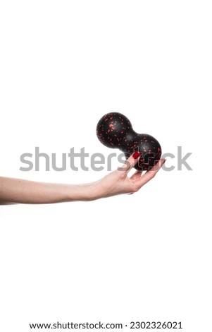 Black double ball or peanut ball massager in female hand. Sports equipment for fitness. Isolated on a white background. High quality photo