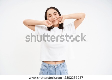 Smiling pleased korean woman, stretching her hands with pleased face, waking up from nap, standing over white background.