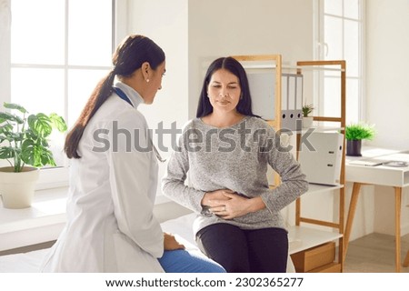 Patient suffering from stomach ache having consultation with female doctor in medical office. Young woman visiting gastroenterologist, gynecologist, therapist, GP in medical clinic Royalty-Free Stock Photo #2302365277