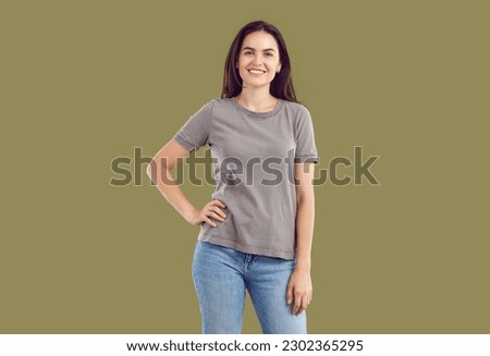 Portrait of beautiful happy, smiling, young brunette dressed in T-shirt and blue jeans, looking at the camera. Confident pose and a look at the camera on an isolated background in the studio. Royalty-Free Stock Photo #2302365295