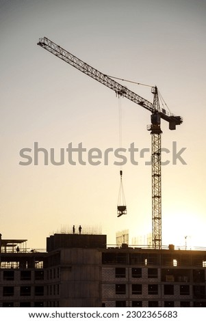 Silhouette of industry crane on creation site house building at sunset, aerial view. Industrial crane on construction site. Construction and renovation of buildings concept. Copy ad text space, poster