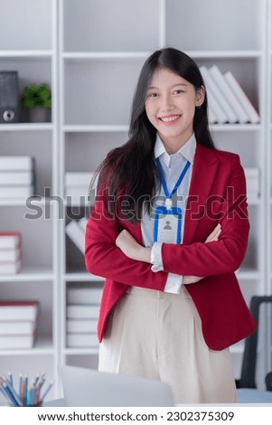 Sharing good business news. Attractive young businesswoman talking on the mobile phone and smiling while sitting at her working place in office and looking at laptop