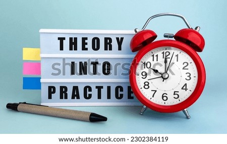 Text Theory into practice written on the lightbox with alarm clock and colorfull stickers on blue background