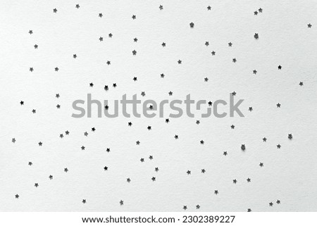 Holiday greeting card.	Christmas, New Year party mockup scene with silver star shape glittering confetti and empty space. Gray paper background.