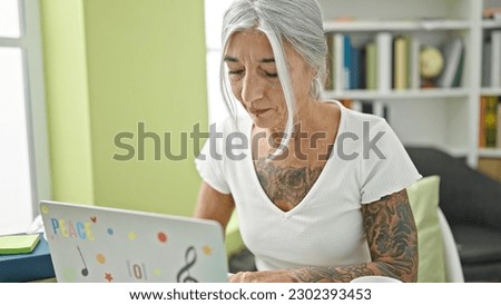 Middle age grey-haired woman student using laptop at library university