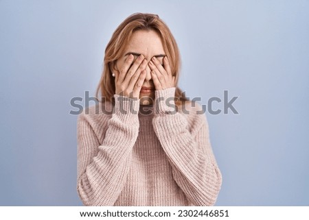 Hispanic woman standing over blue background rubbing eyes for fatigue and headache, sleepy and tired expression. vision problem 