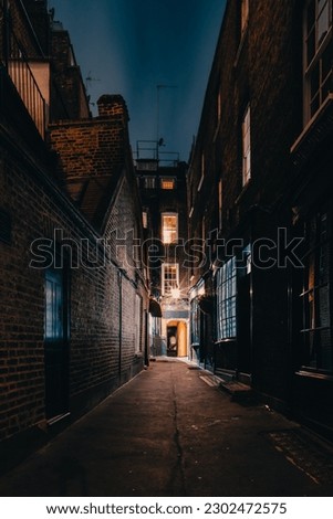 A mysterious and hidden old back alley in London at night Royalty-Free Stock Photo #2302472575