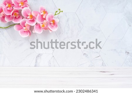 Wooden floor and pink color orchid decorate on marble background, empty room for background.