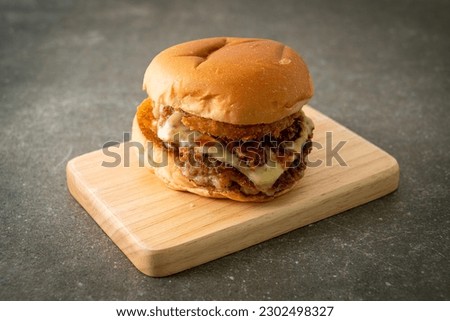 pork burger with cheese, bacon and onion rings on wood board