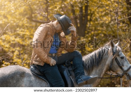 A cowboy with a hat on a white horse