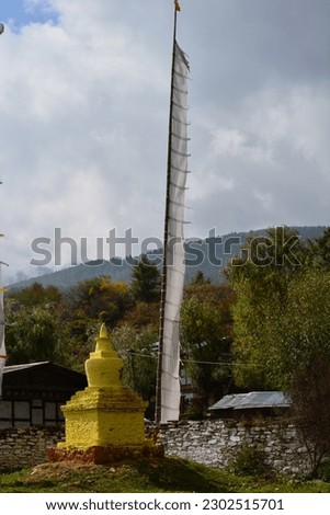 Bhutan - small yellow stupa and a large white praying flag