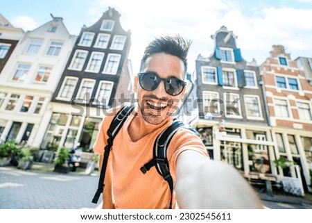 Happy tourist taking selfie picture in Amsterdam, Netherlands - Cheerful man using smart mobile phone device outside - Student traveler enjoying summer european vacation - Life style tourism concept