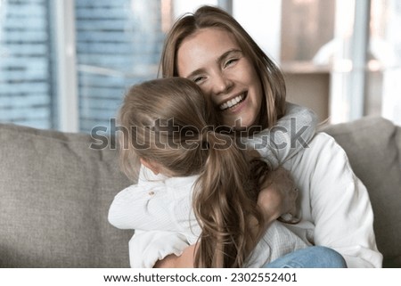Beautiful young mom hugging little girl kid with love, affection, care, looking at camera, smiling, laughing, enjoying motherhood, family bonding, warm relationship