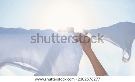 Woman hands hangs laundry on clothesline Royalty-Free Stock Photo #2302576277
