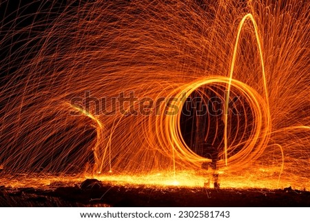 Long exposure photographic images with the steel wool technique made by rotating fire in the dark at night